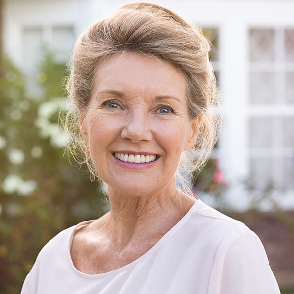 an old lady with a ponytail smiling showing her dental implants