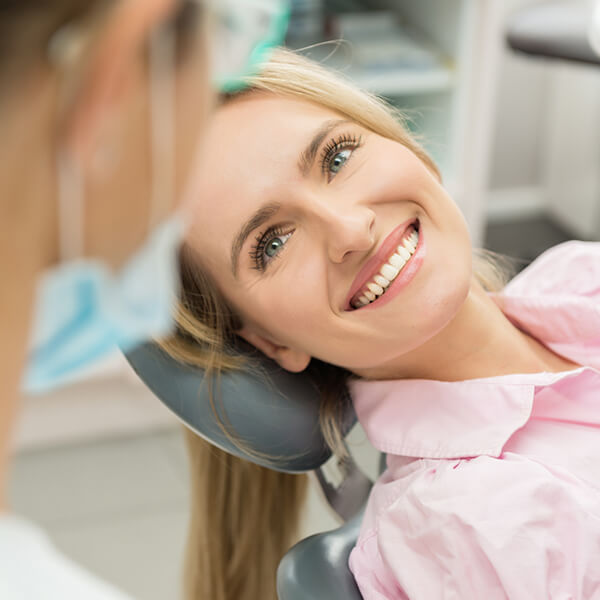 Lady lying on a dental chair A smiling lady is lying on a dental chair and looks on to her dentist