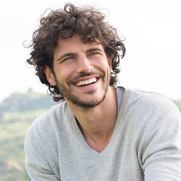 Invisalign in hand A smiling person is holding an Invisalign with his left hand
