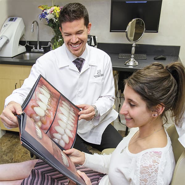 Dr.Nosti Showing Smile Album Dr.Nosti is showing an album of smiles to a lady patient