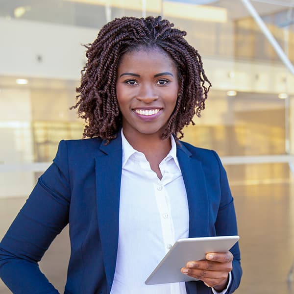 Lady holding a tablet A lady with short curly hair and wearing a blazer is holding a tablet