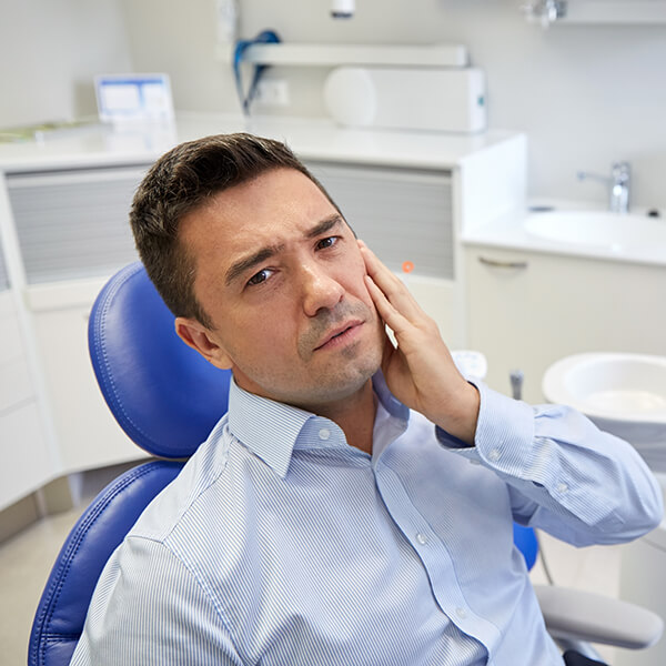 Man in Pain A man sitting on a dental chair is in pain and holding his left cheek
