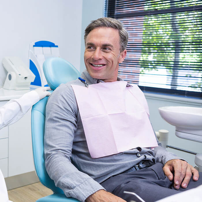Man with dental bib A man on a dental chair wand wearing a dental bib is looking at his right